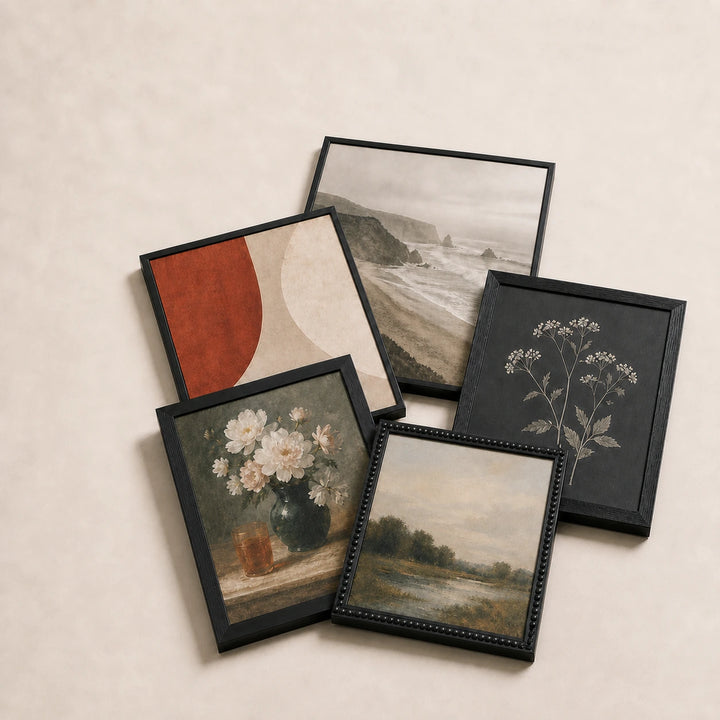 A collection of black picture frames lying flat with varied edge-to-edge artwork