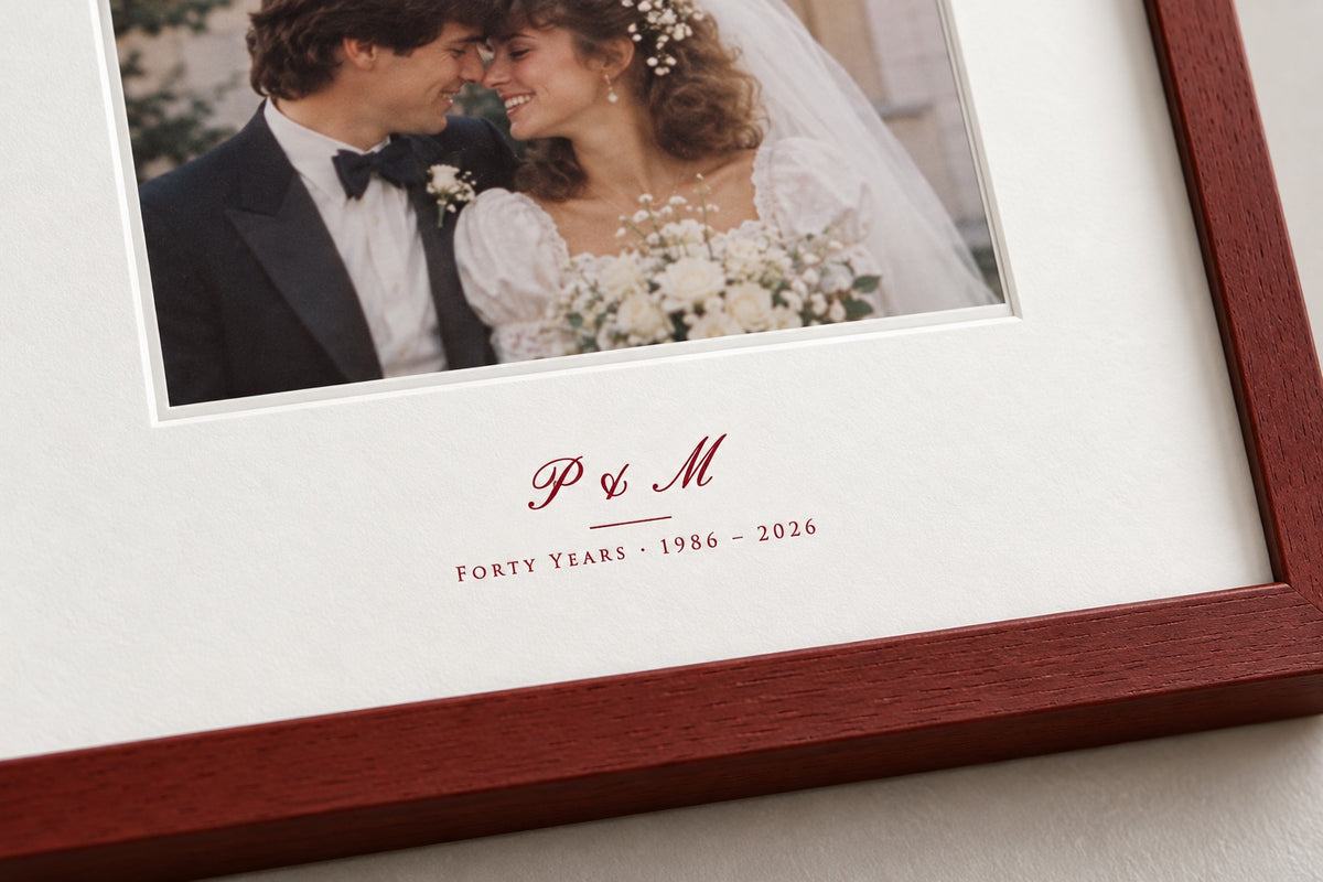 Close-up of the initials P & M and "Forty years 1986 – 2026" printed in ruby-red ink on the mount
