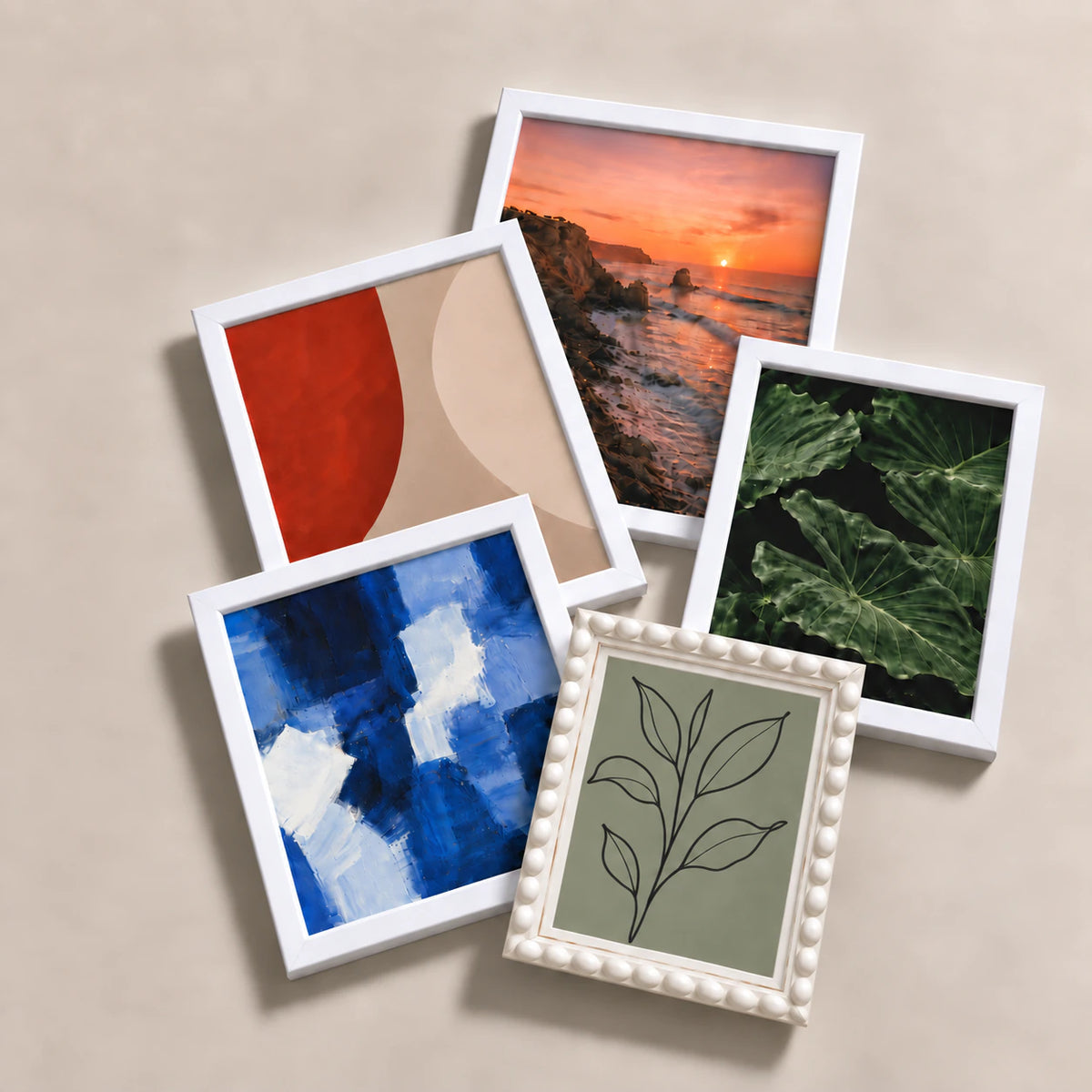 A collection of white picture frames lying flat with varied edge-to-edge artwork