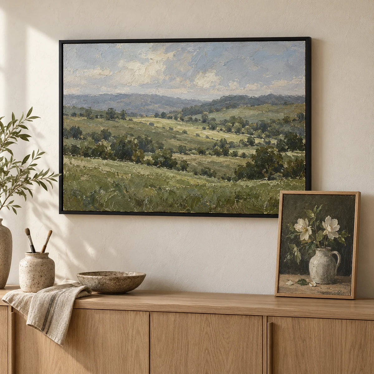 Canvas board paintings framed edge to edge in slim black and natural wood frames above an oak sideboard
