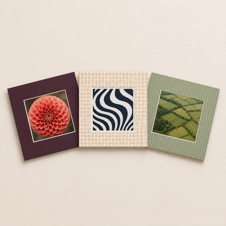 Three square picture mounts in plain and patterned finishes holding varied artwork
